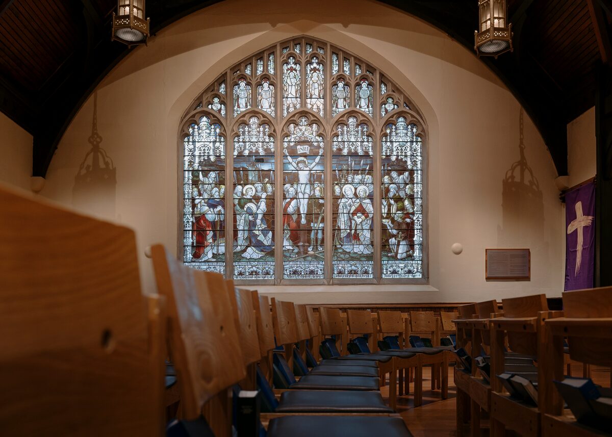 Sunlight through a stained glass window above empty pews